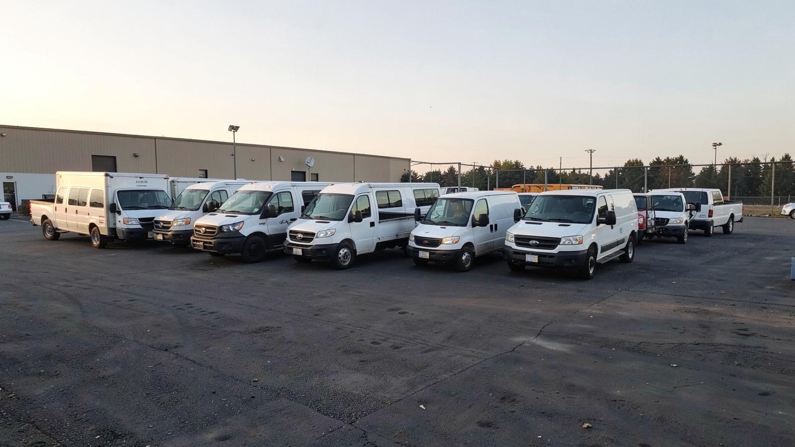Work vans and pickup trucks parked in a row at a contractor yard